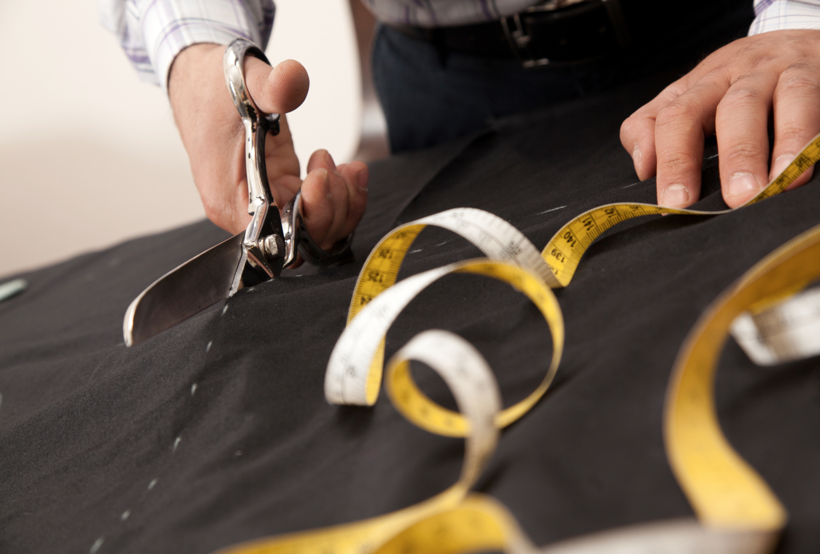 A man in a tan suit is adjusting his tie