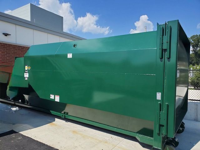 Green commercial dumpster near a building.