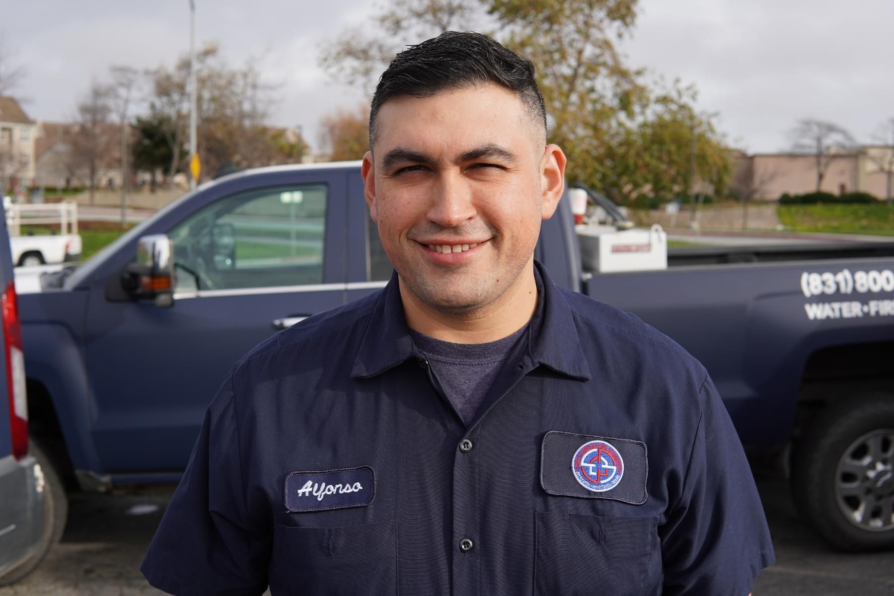 a man in a blue shirt is standing in front of a blue truck .