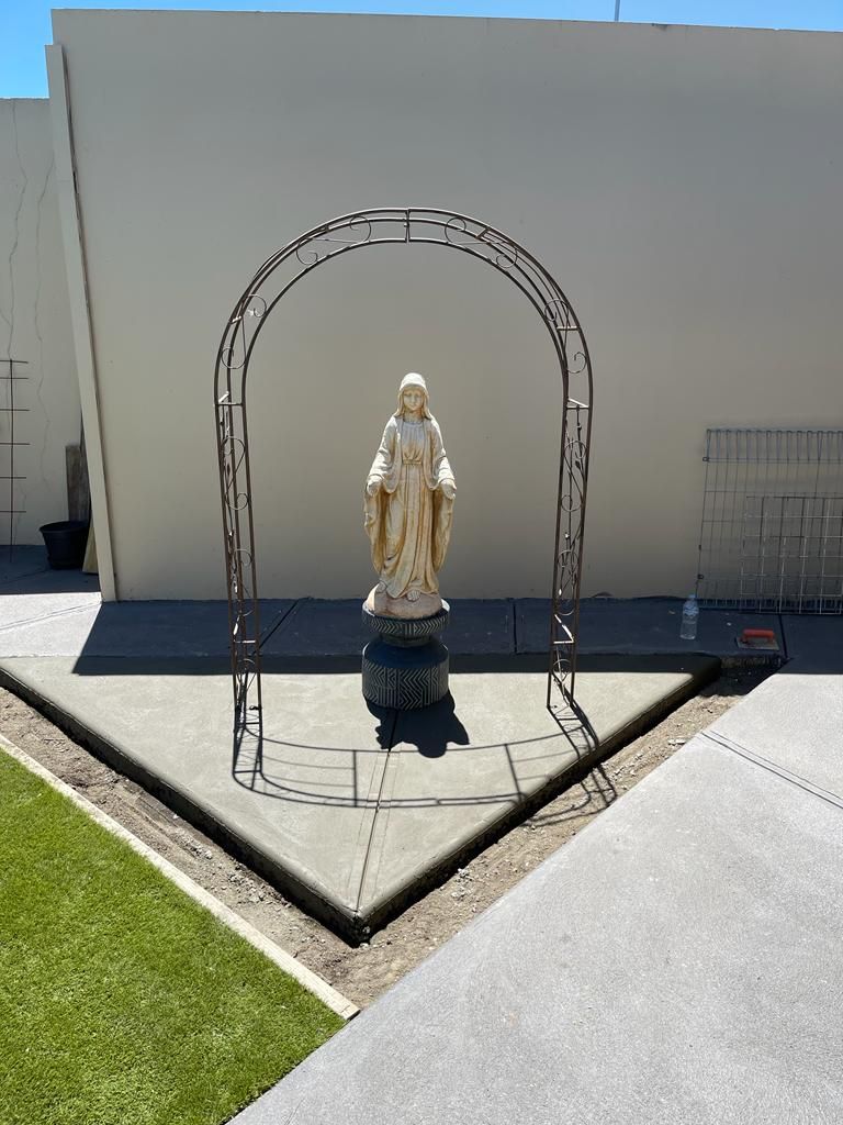 A statue is sitting under a metal arch in front of a building.