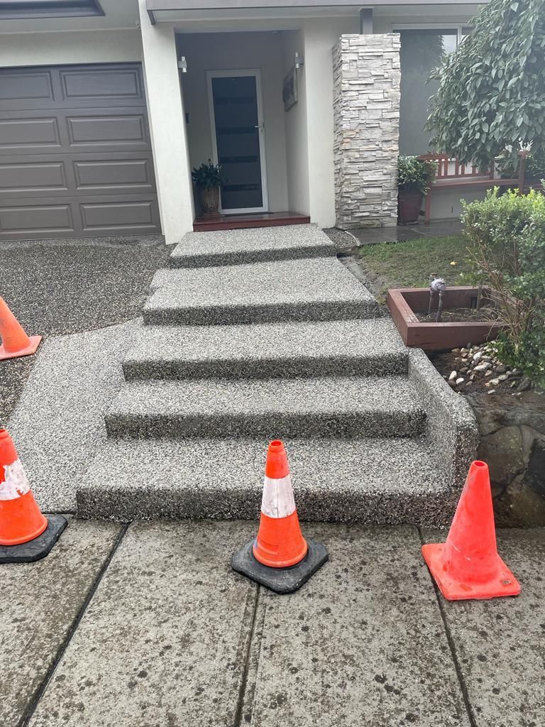A set of stairs with orange cones on the sidewalk in front of a house.
