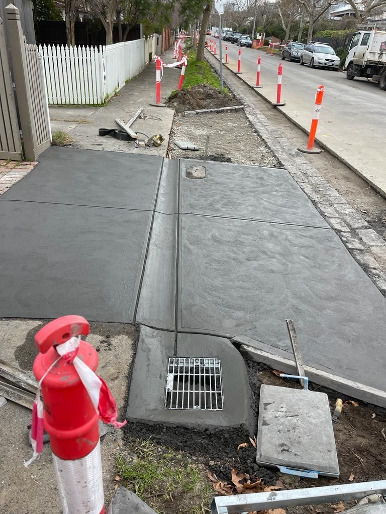 A red and white fire extinguisher is sitting next to a drain on the side of a road.