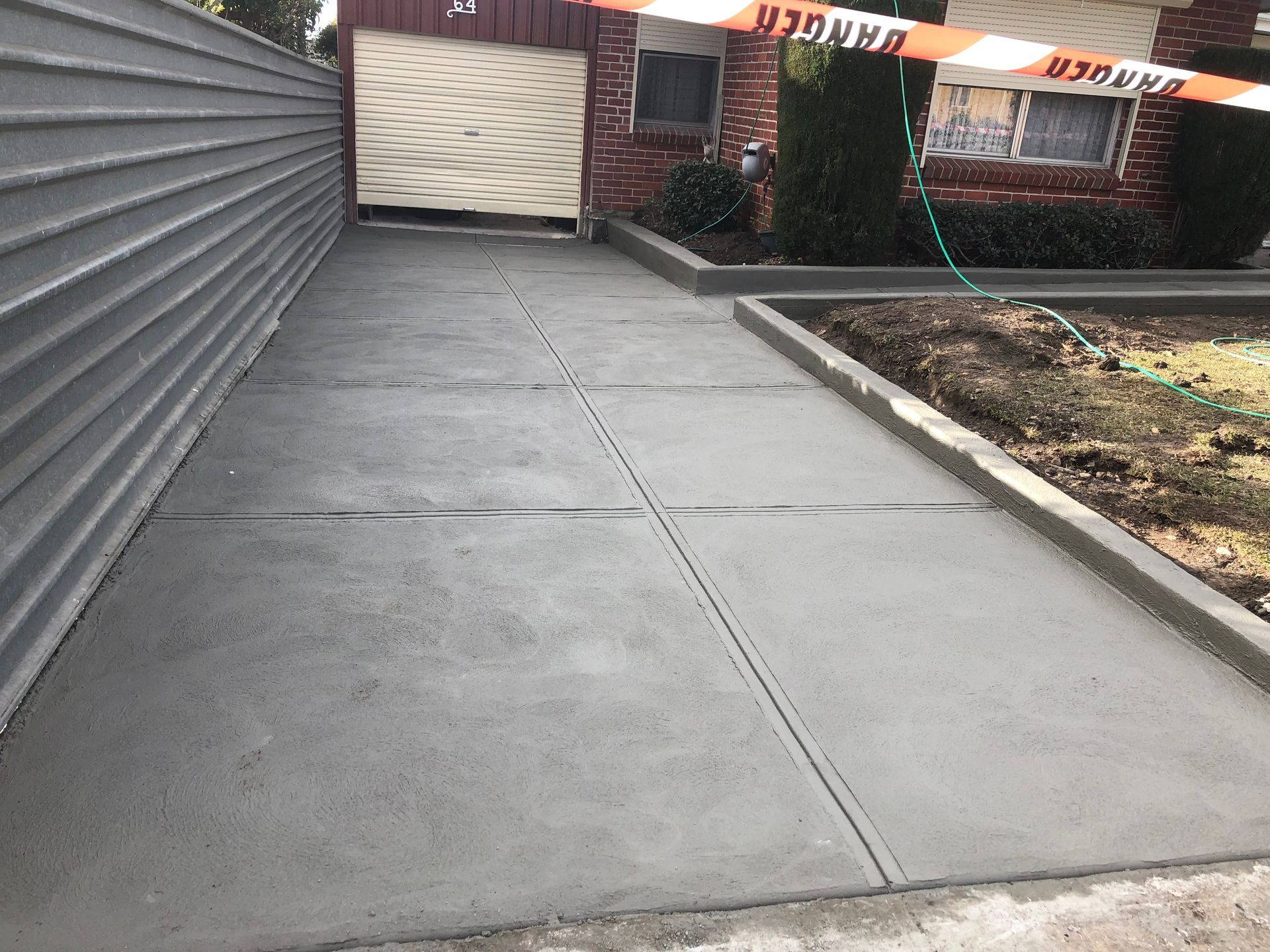 A concrete driveway leading to a garage next to a house.