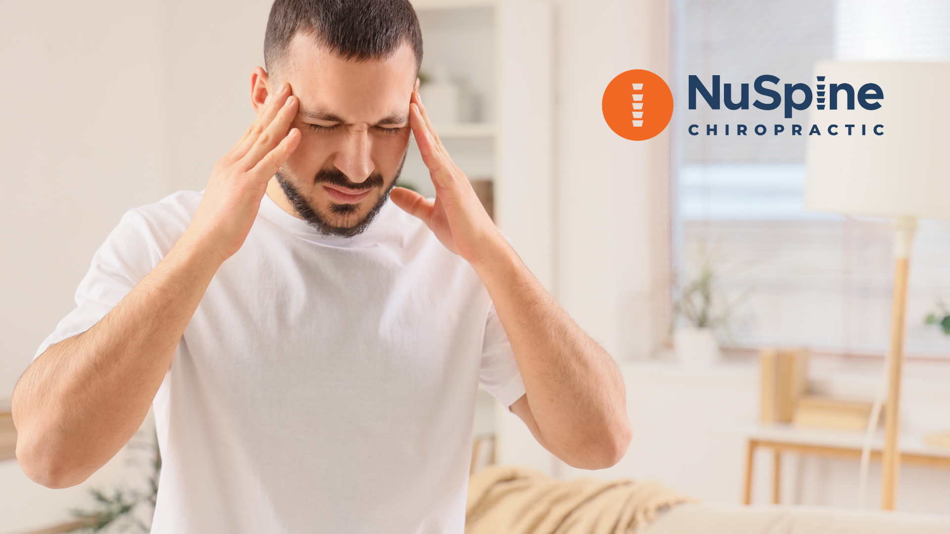 A person with a pained expression holding their head with both hands in a bright, modern room, with a NuSpine logo.