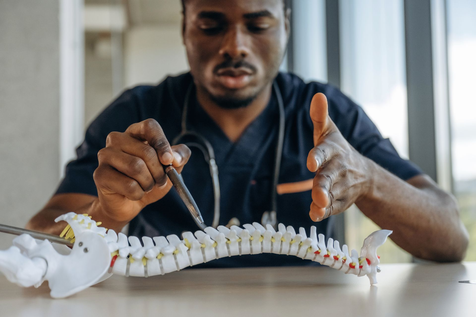 A doctor is examining a model of a human spine with a stethoscope.