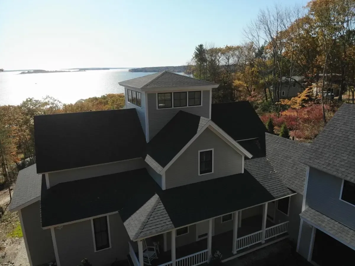An aerial view of a house with a large porch overlooking a body of water.