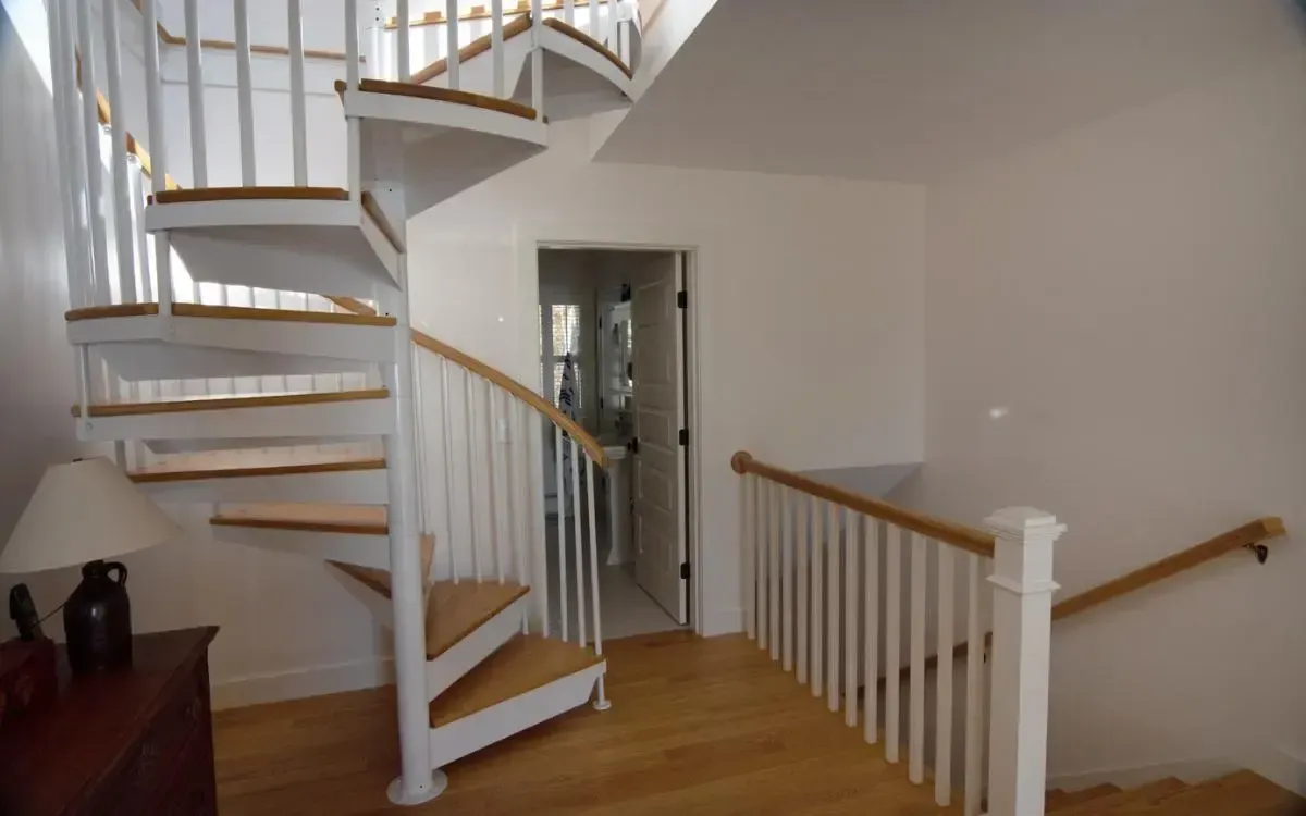 A spiral staircase with wooden steps and white railing