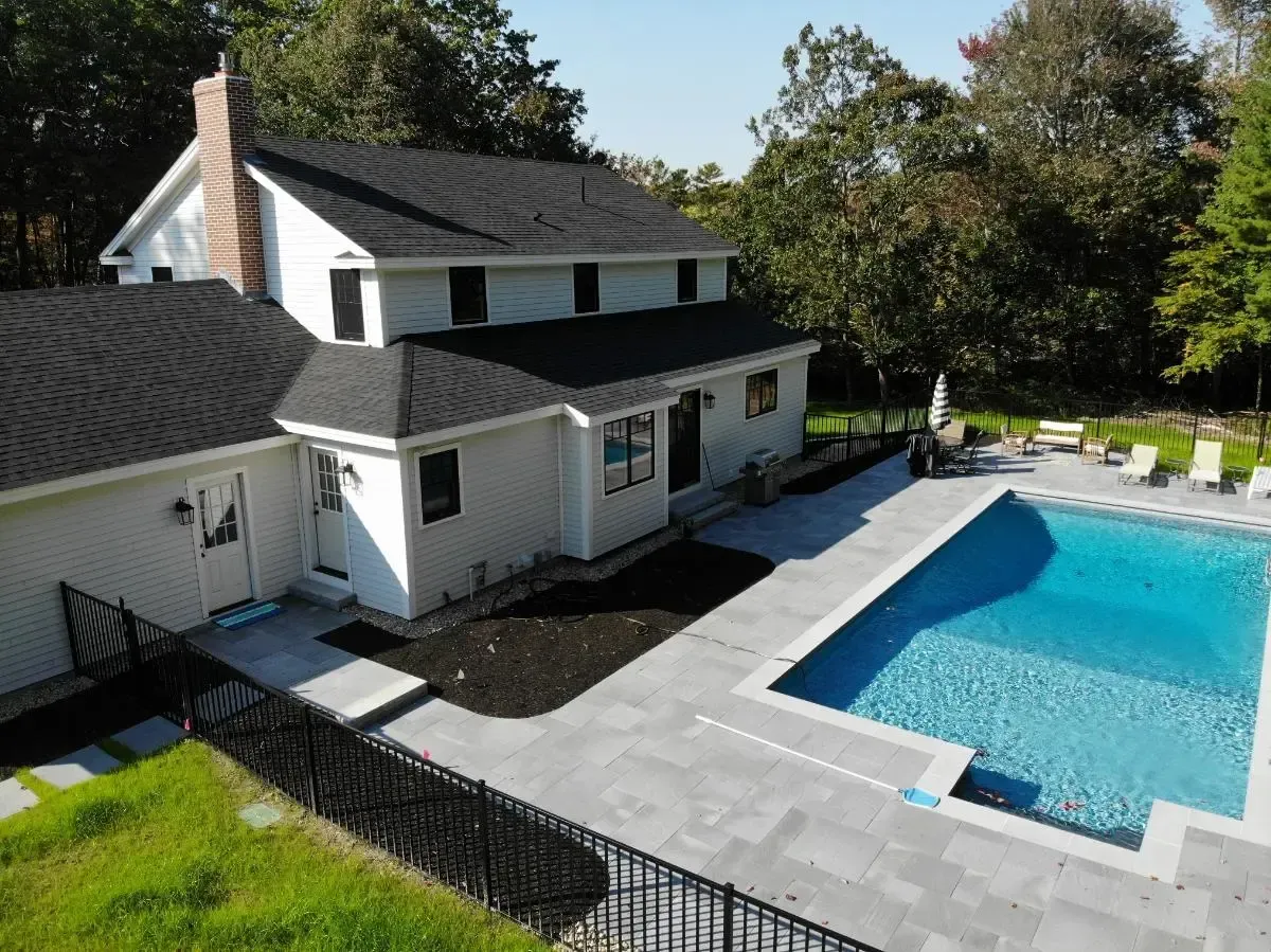 An aerial view of a house with a large swimming pool in the backyard.