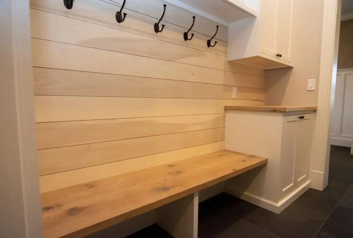 A mud room with a wooden bench and hooks on the wall.