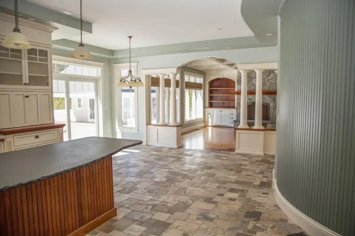 An empty kitchen with a large island and a tiled floor.