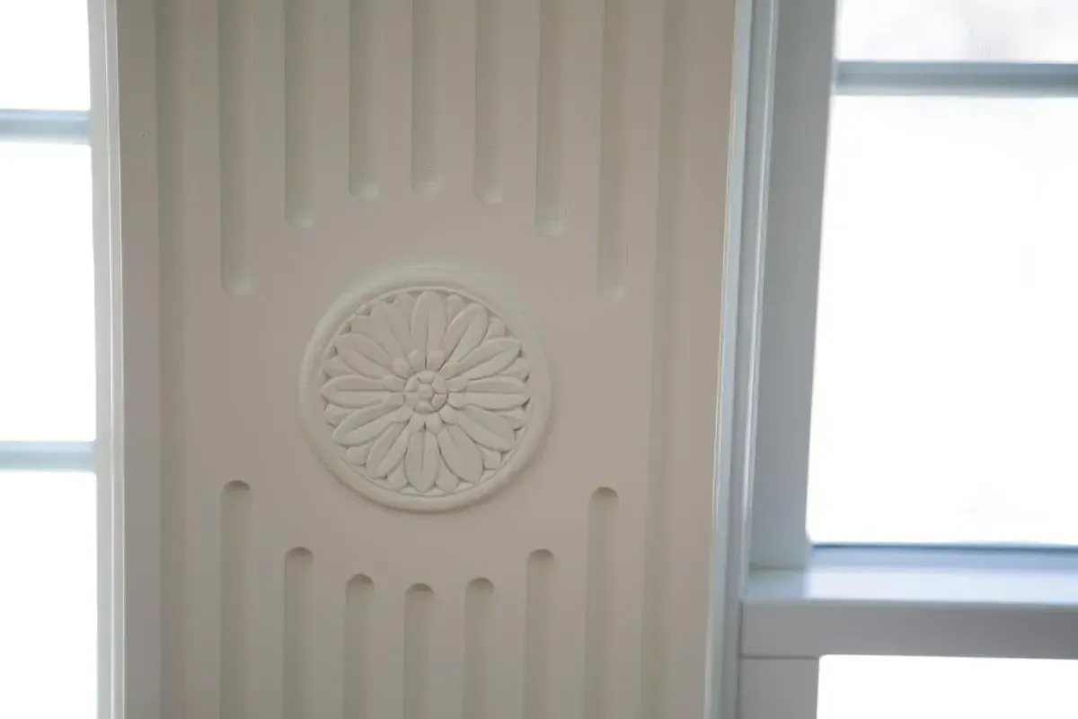 A close up of a white wall with a circular design on it.