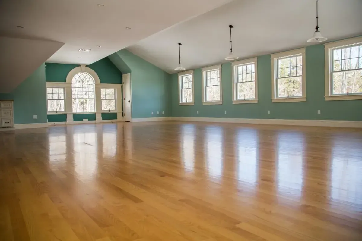 A large empty room with hardwood floors and green walls.
