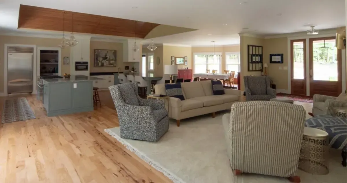 A living room with a couch and chairs and a kitchen