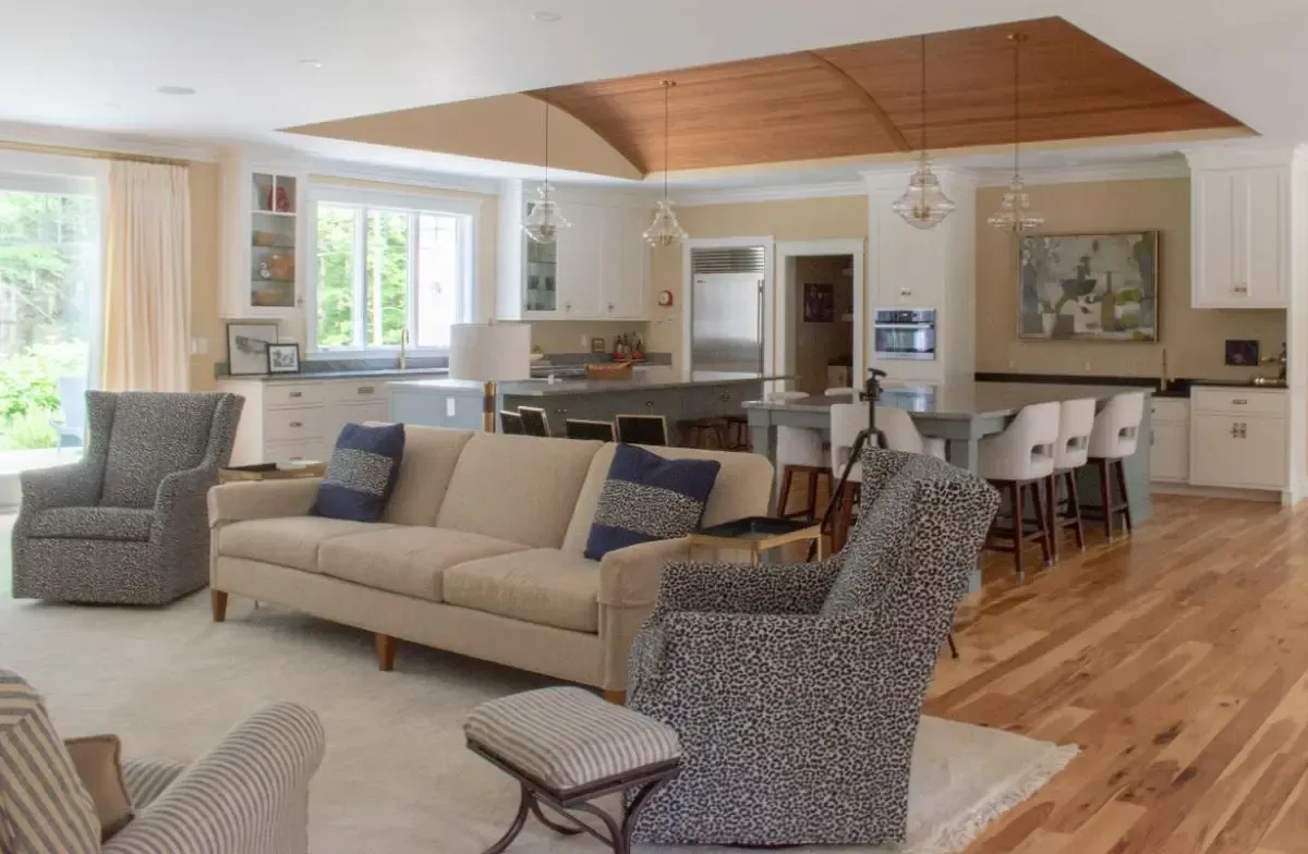 A living room with a couch and chairs and a kitchen in the background