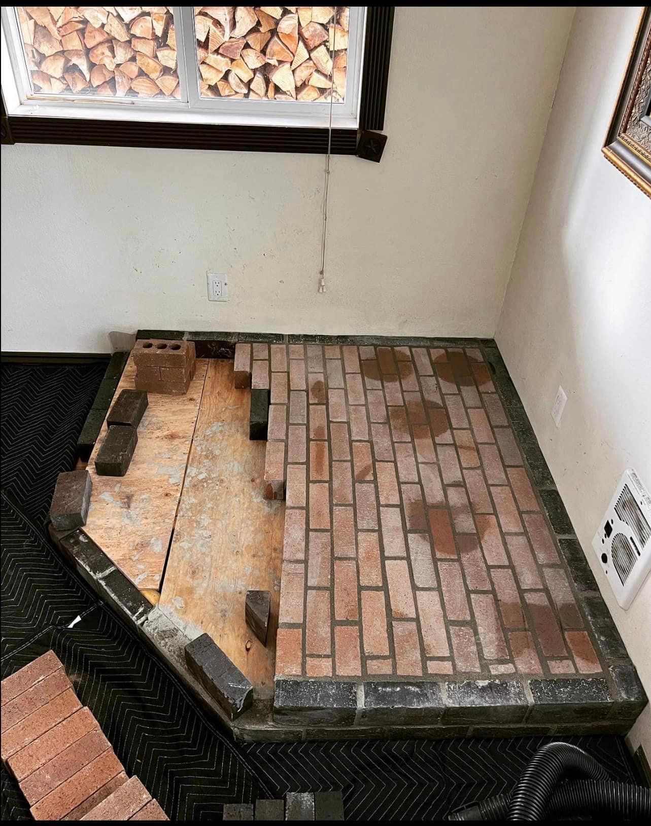 A brick floor is being built in a room next to a window.