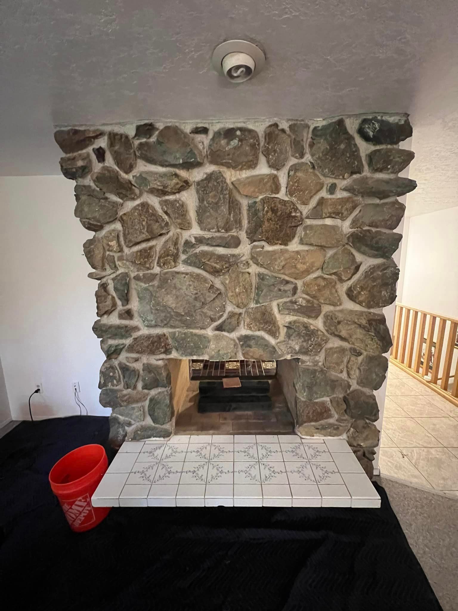 A stone fireplace in a living room with a table in front of it.