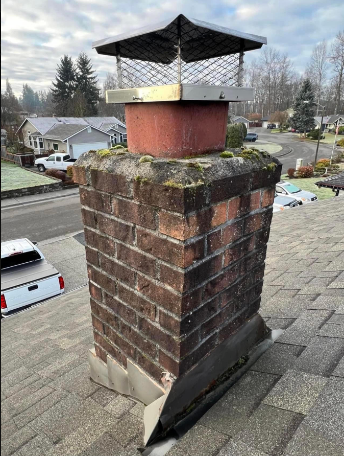 A brick chimney is sitting on top of a roof.