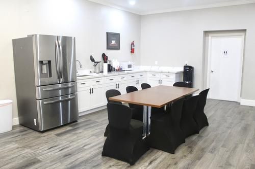 Kitchen with a refrigerator, cabinets, a table, chairs, and a restroom door.
