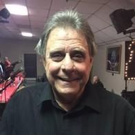 A man in a black shirt is smiling in a room.