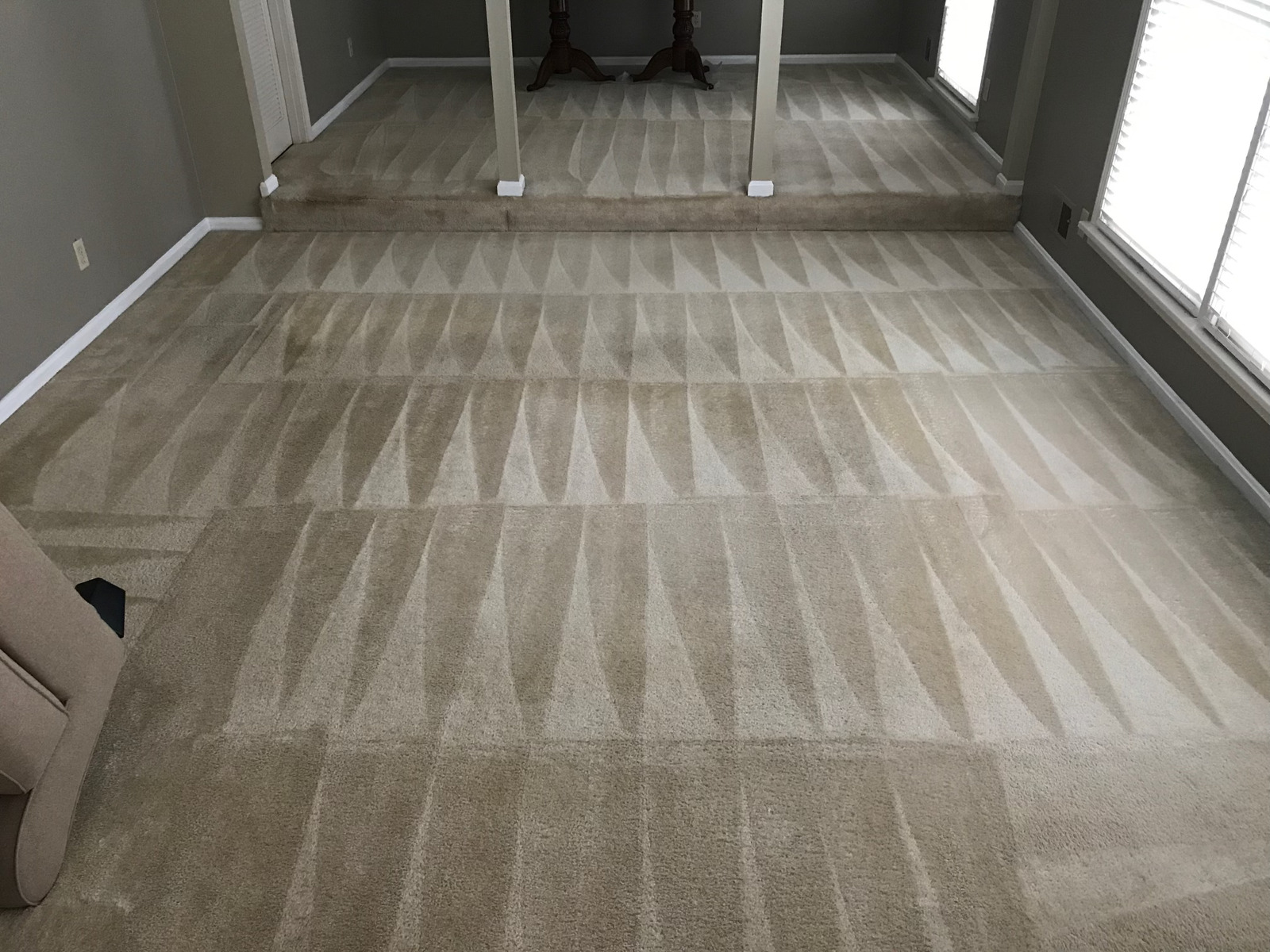 A living room with a carpeted floor and a mirror.