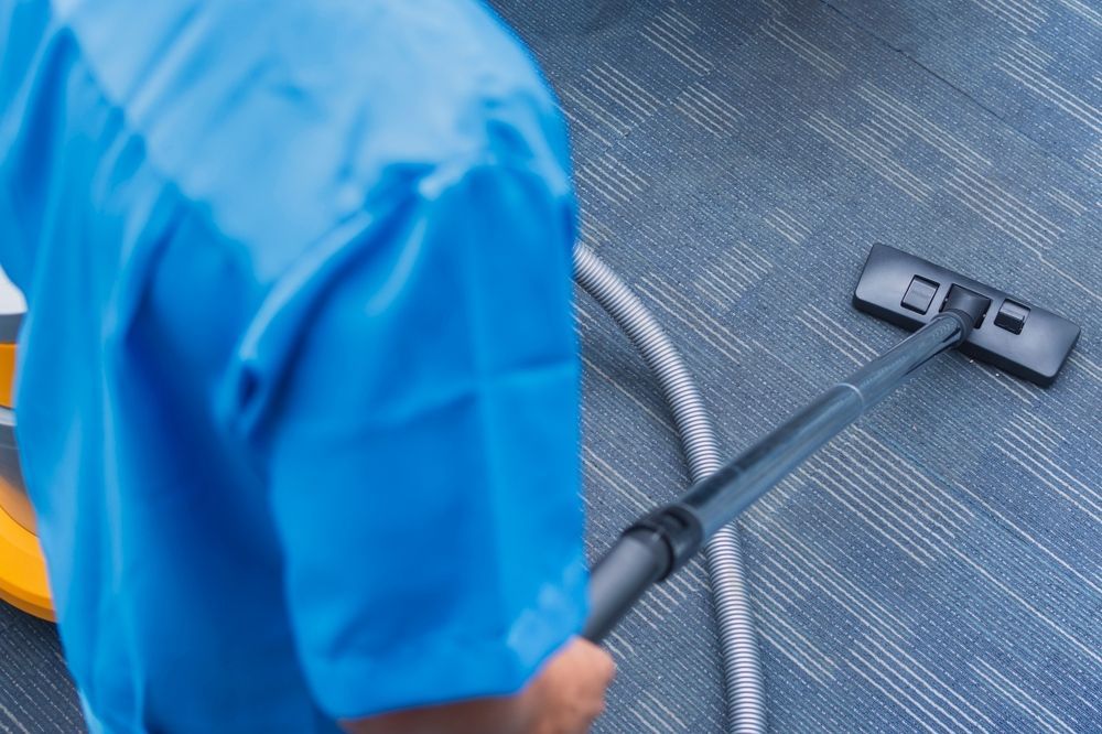 Worker using a commercial vaccum to clean a dirty floor surface