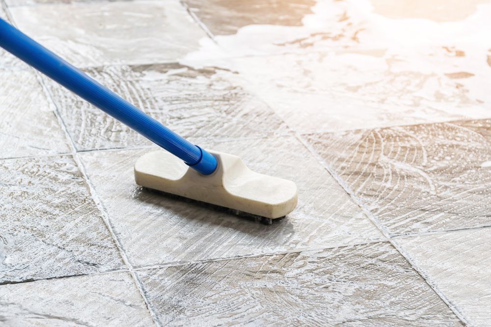 A broom is being used to clean a tiled floor.
