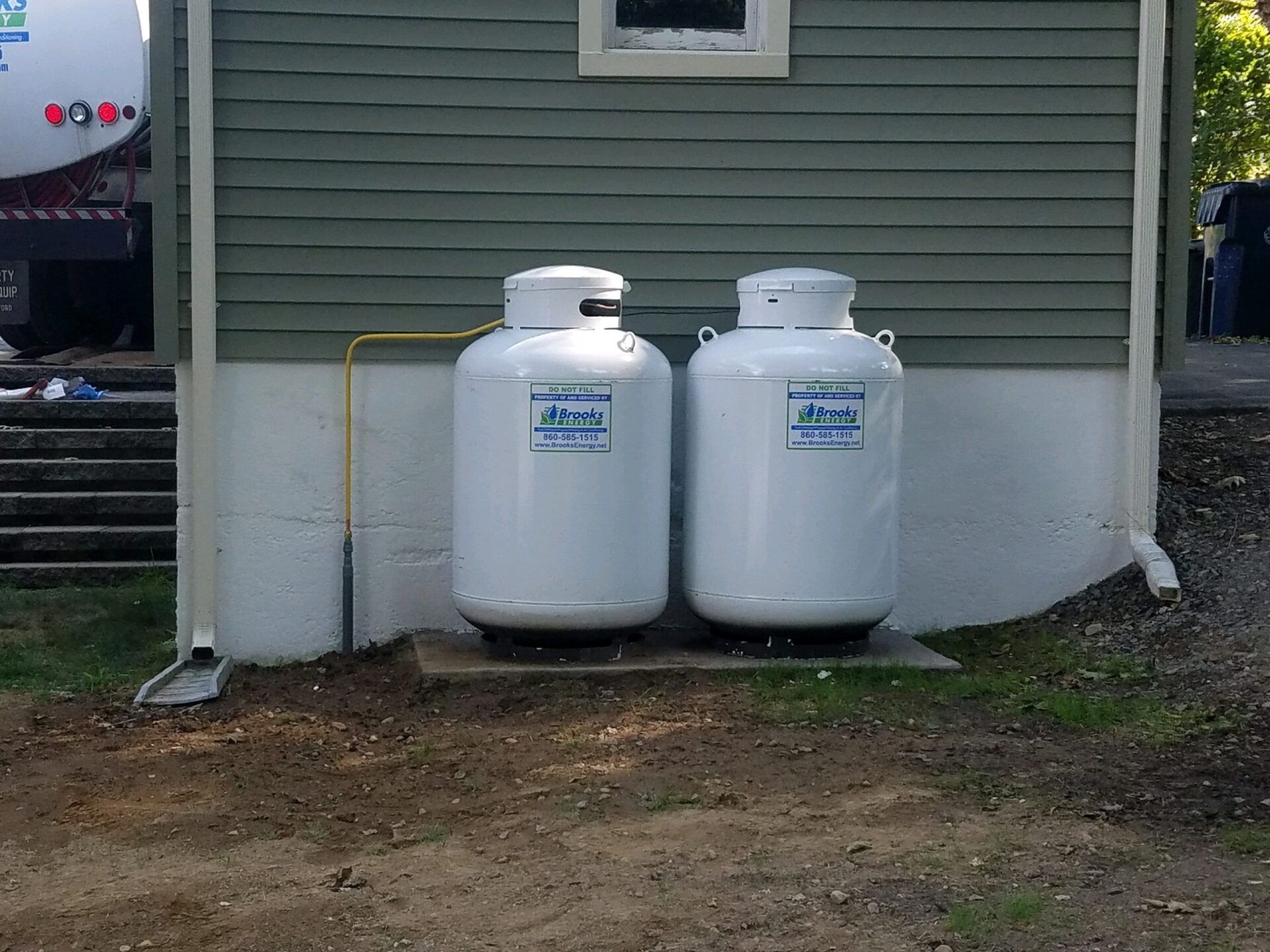 Two propane tanks are sitting on the side of a house.
