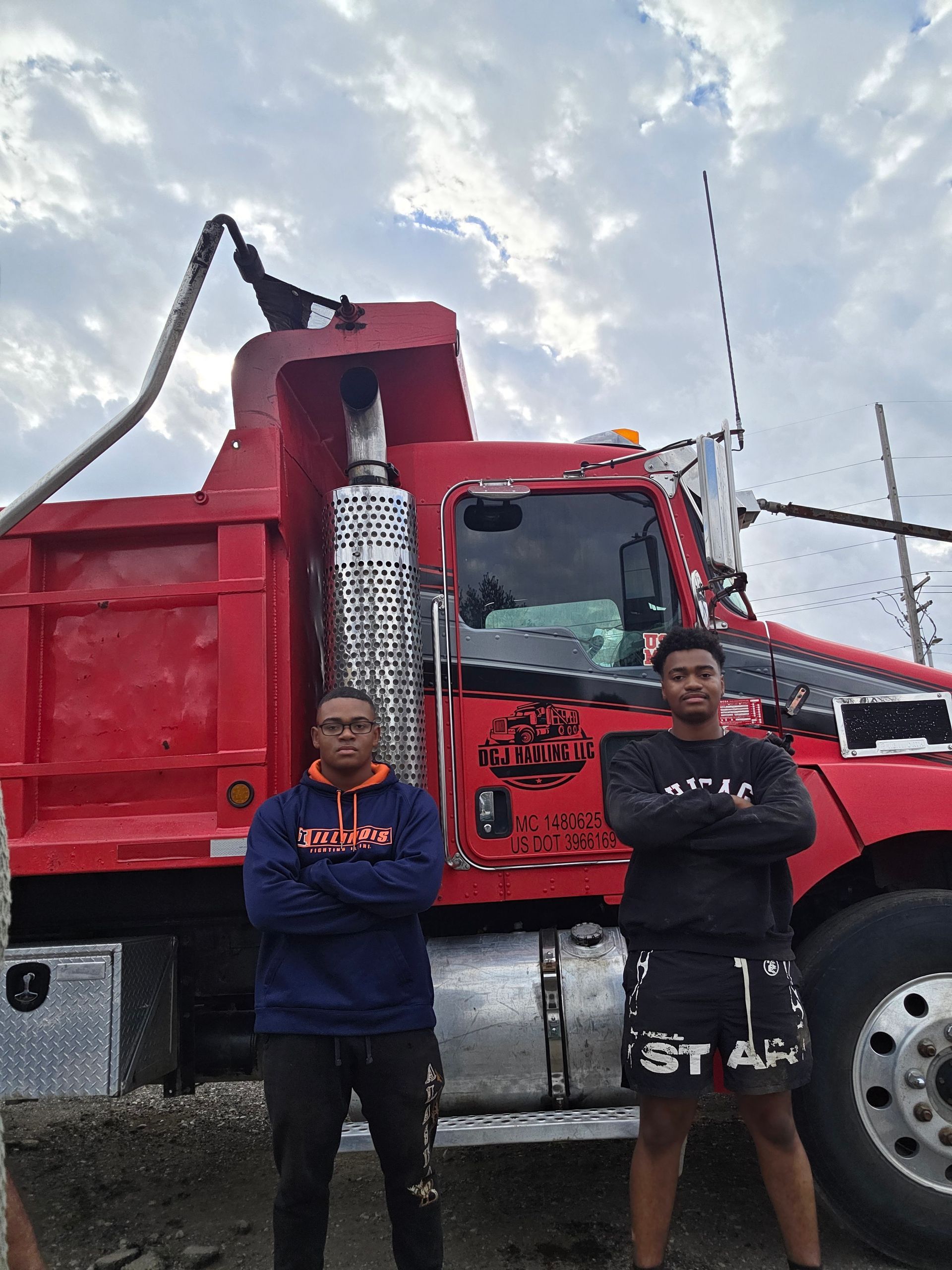 A line of red and blue semi-trucks parked on a gray lot under a cloudy sky.