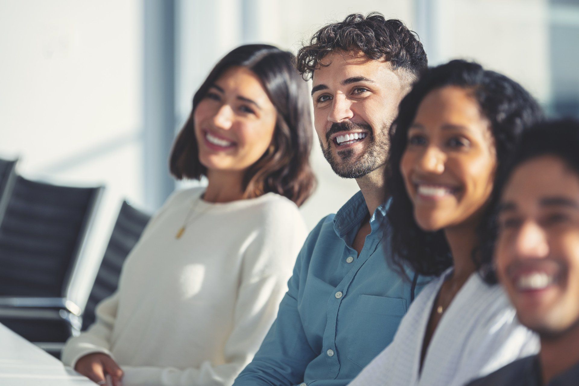 Smiling coworkers seated in a bright office, looking toward the camera