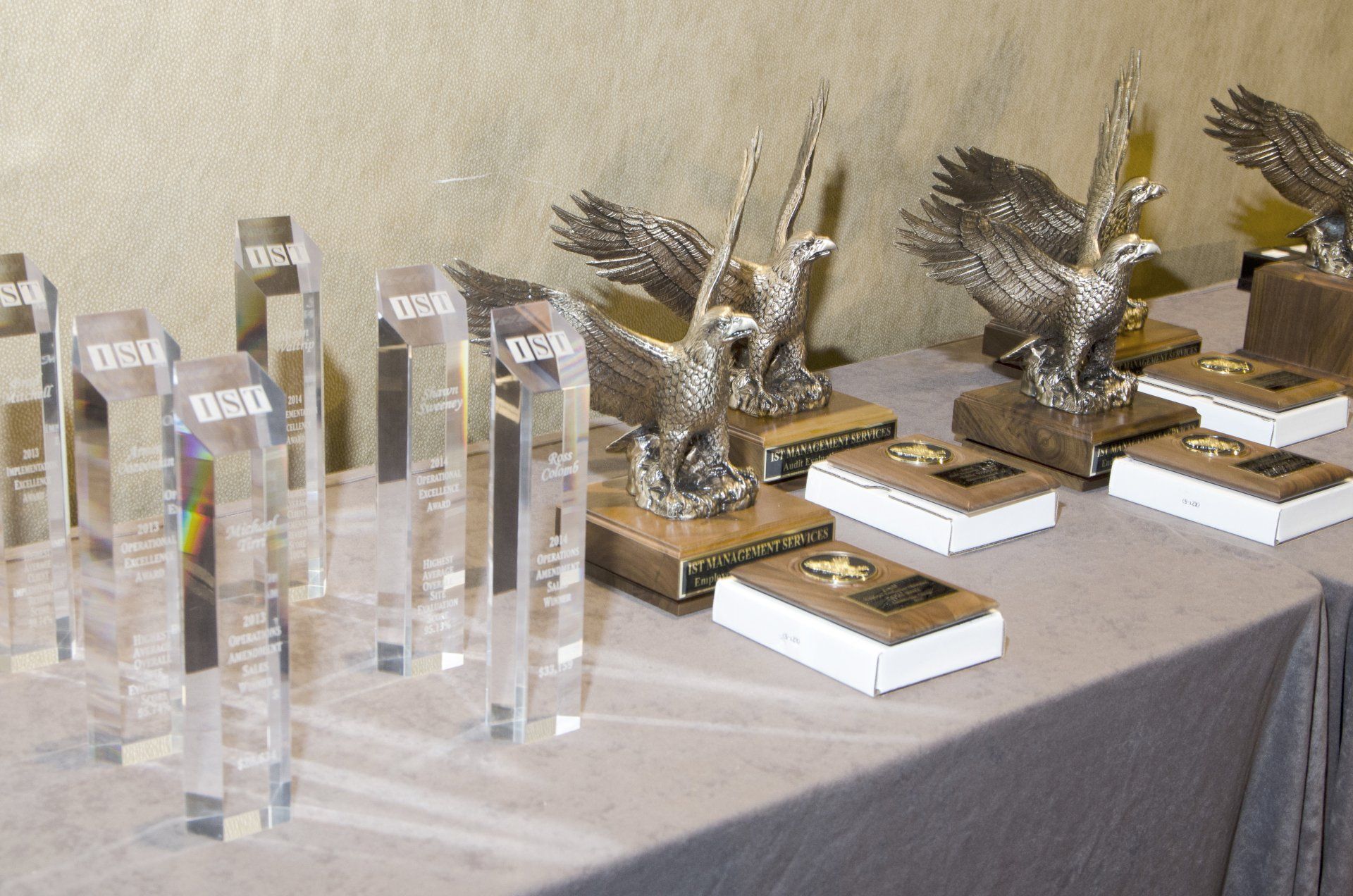 Trophy display with crystal and winged awards arranged on a table under soft indoor lighting