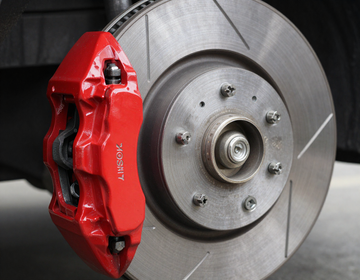 Red brake caliper on a silver car wheel and rotor close-up