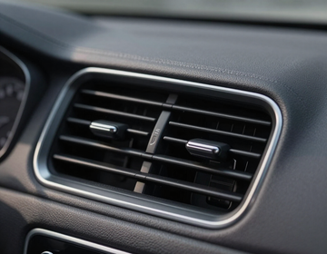 Car dashboard air vent with silver trim and black slats