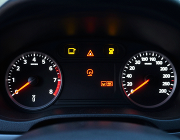 Car dashboard with speedometer, tachometer, and several warning lights illuminated
