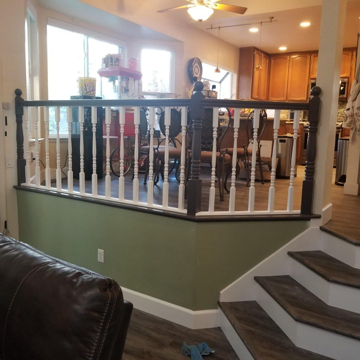 Living room with staircase, black-and-white railing, and open view into the dining area and kitchen.