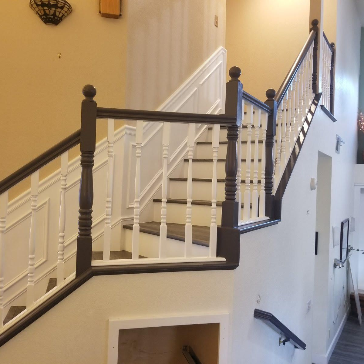 Interior staircase with white balusters and dark wood railings in a beige hallway