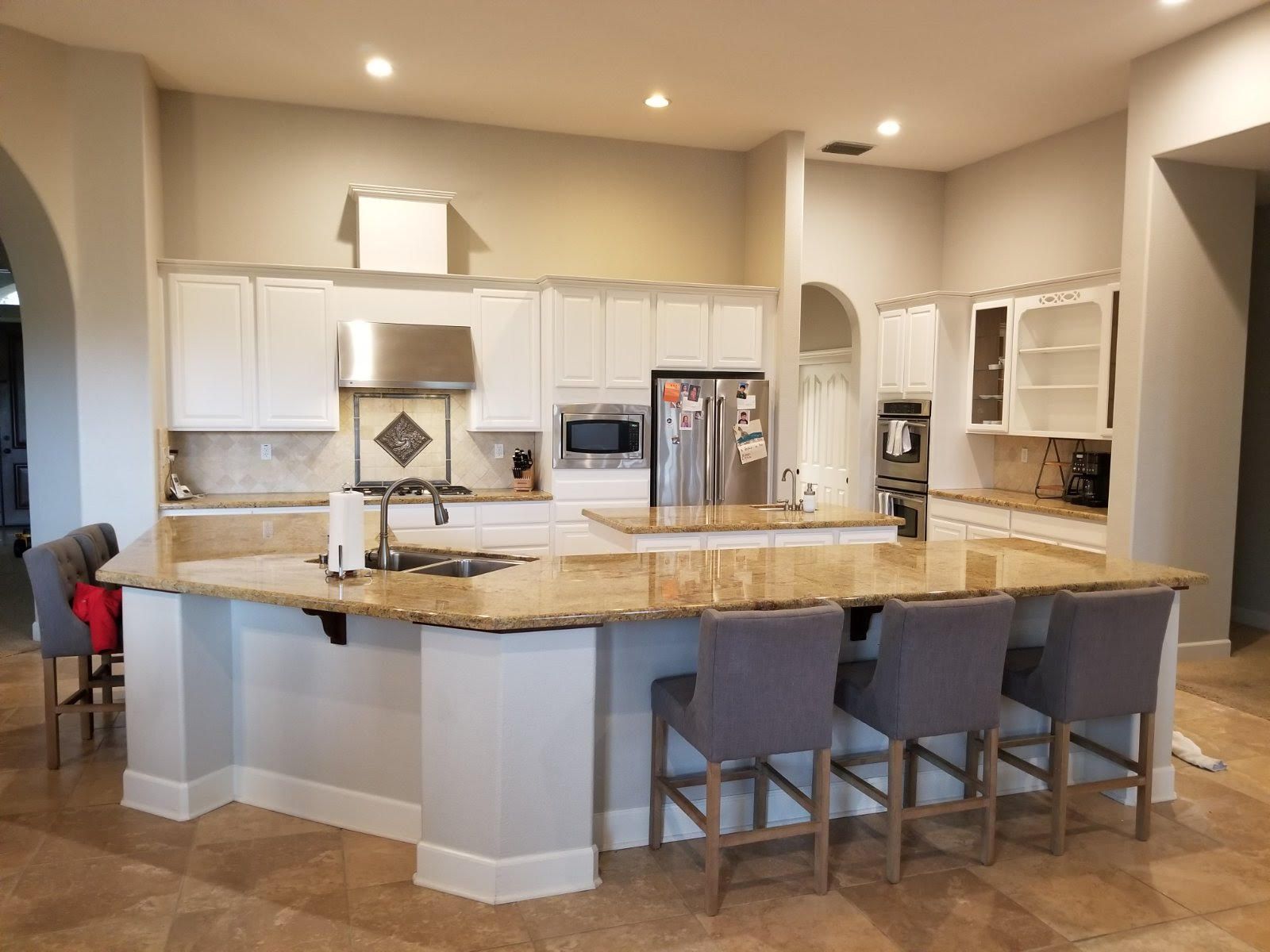 Bright modern kitchen with a large granite island and four gray stools