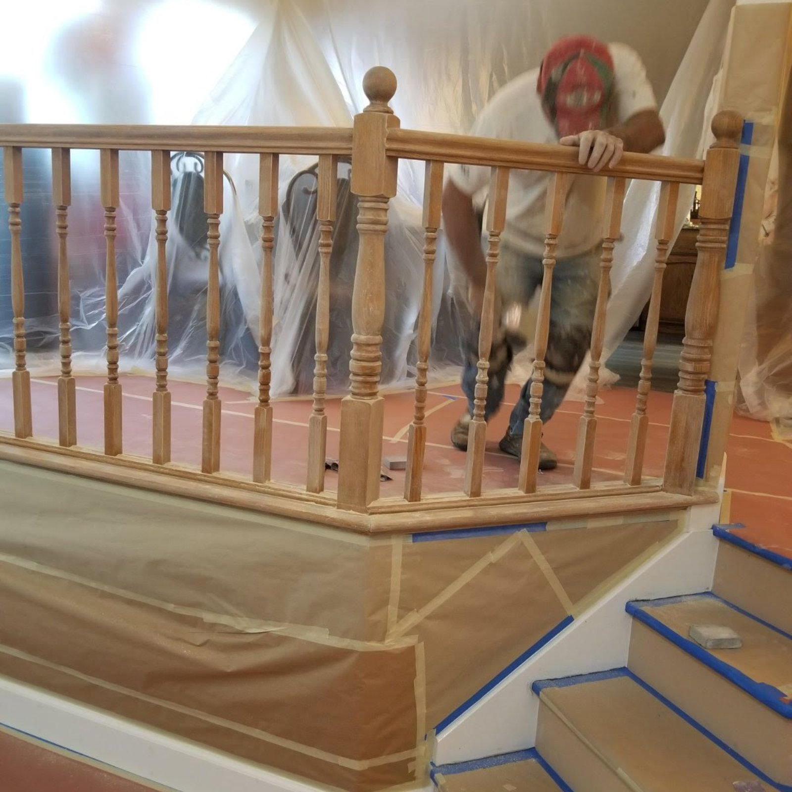 Person climbing a plastic-covered staircase beside a wooden railing during home renovations