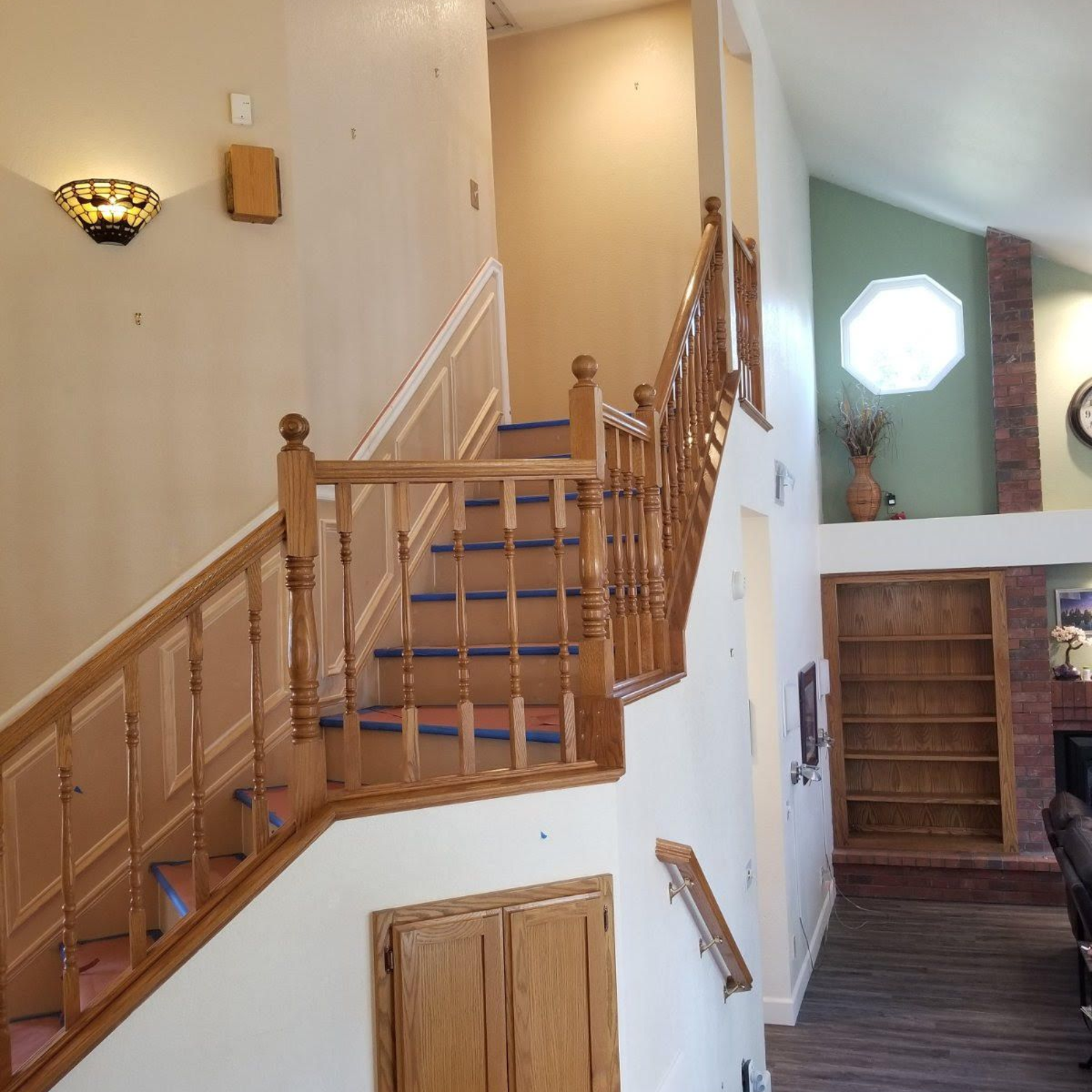 Interior stairway with wooden railing and steps, opening into a bright room with built-in bookshelves.