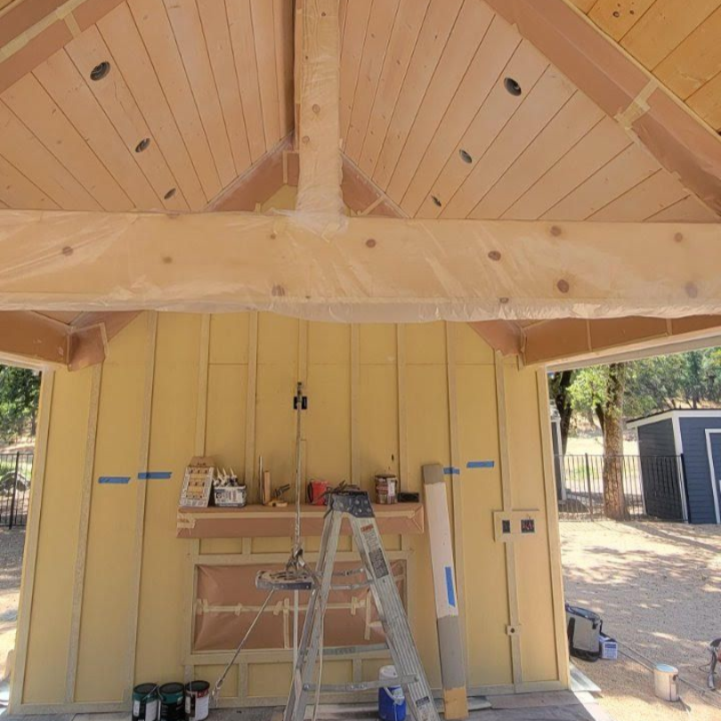 Partially finished porch with yellow walls, exposed wood ceiling, ladder, and tools on the floor