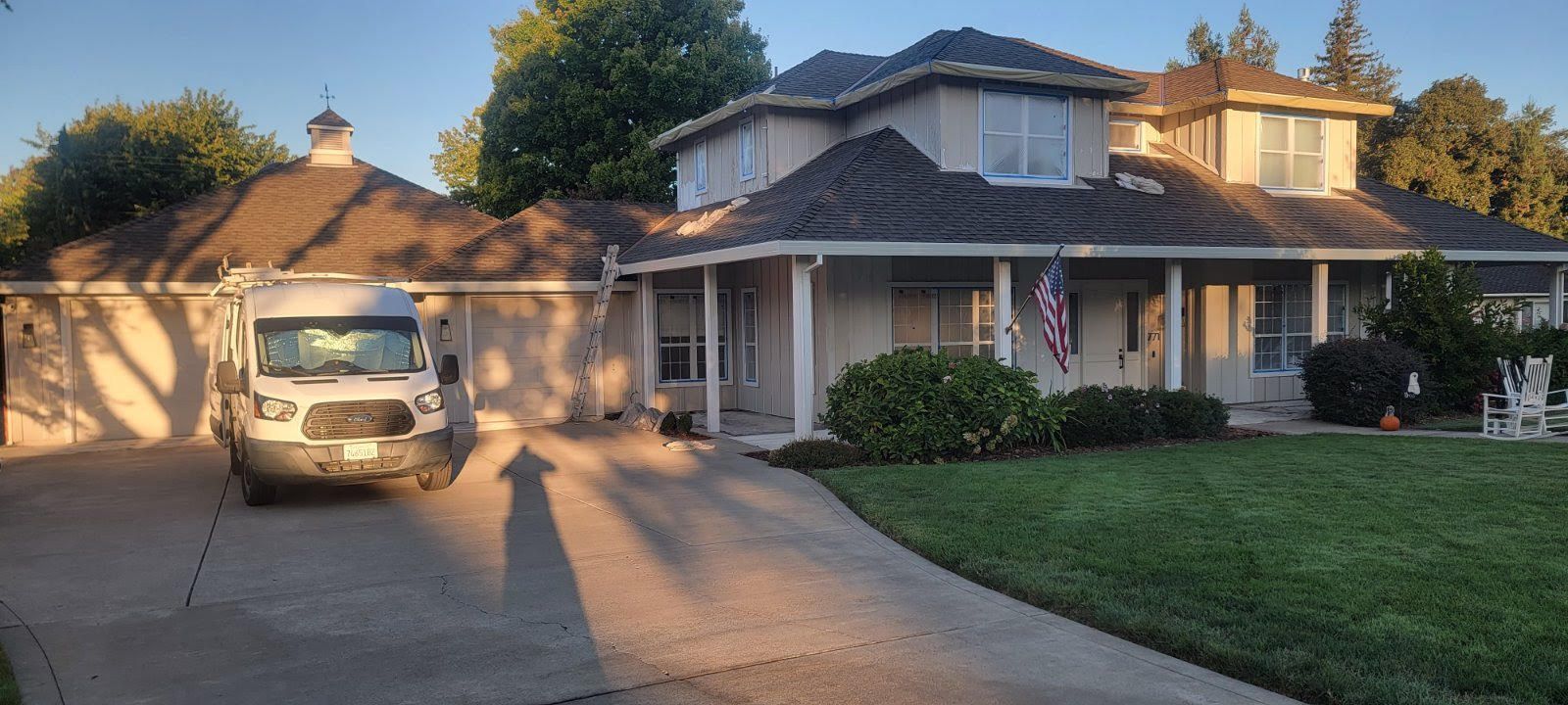 Suburban house at sunset with a car parked in the driveway and a manicured front lawn
