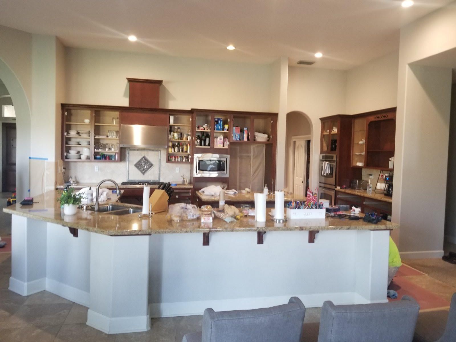 Open-concept kitchen with a large white island, wood cabinets, and stainless appliances under recessed lighting