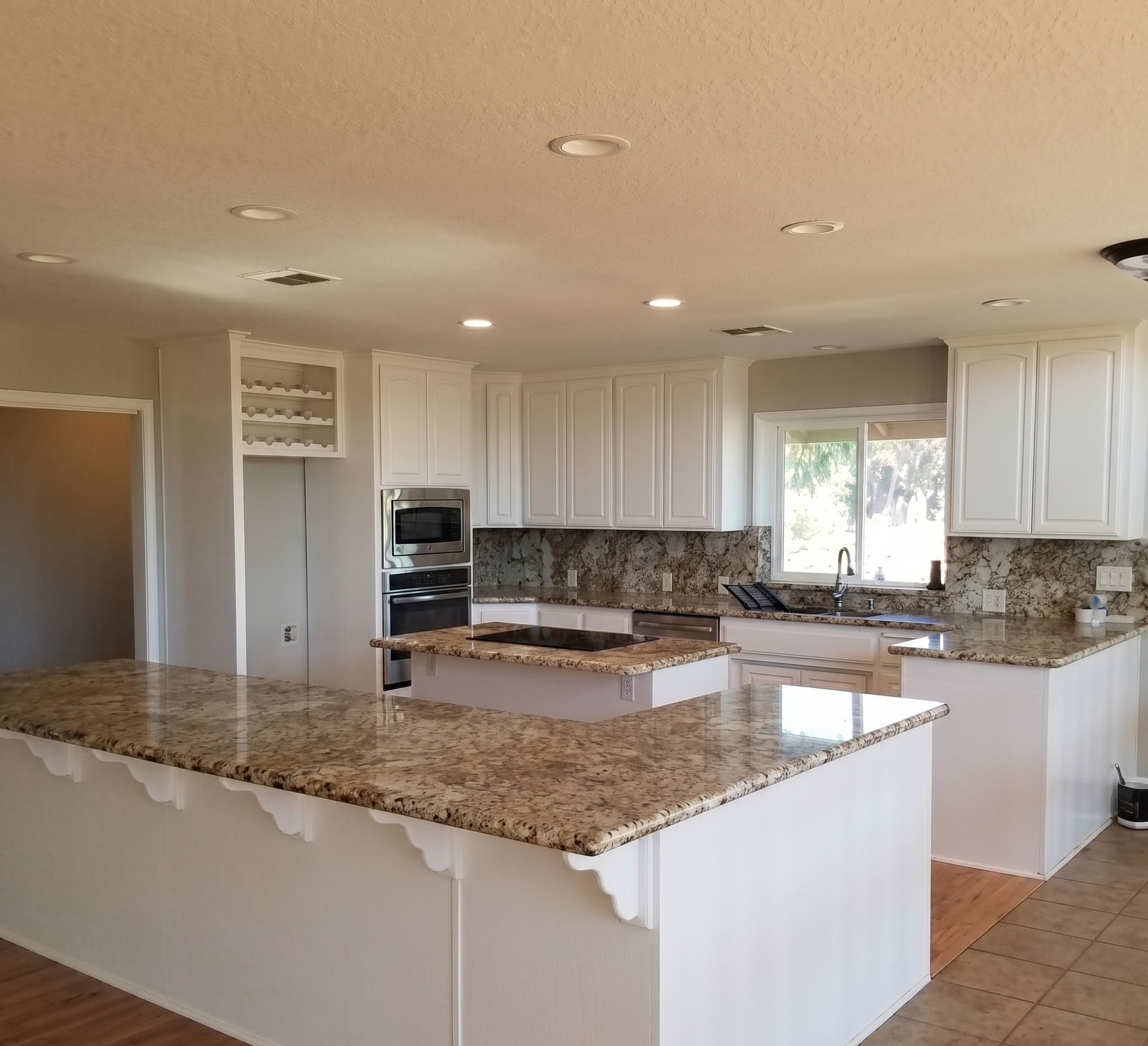 A kitchen with white cabinets and granite countertops.
