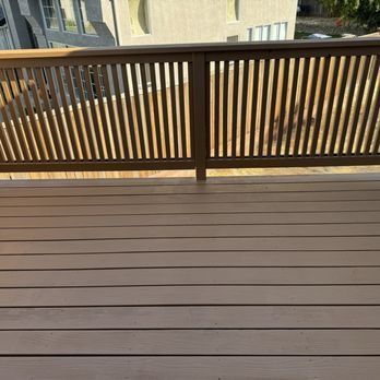 Wooden deck with horizontal planks and dark railing overlooking neighboring buildings.