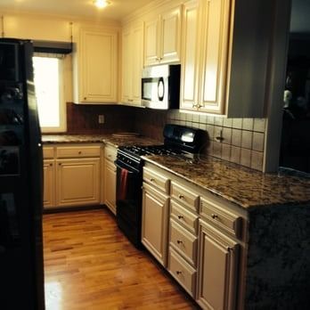 Compact kitchen with cream cabinets, granite counters, stainless stove, and wood floors.