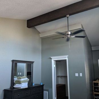 Bedroom with gray walls, ceiling fan, dresser, and an open doorway to a closet.