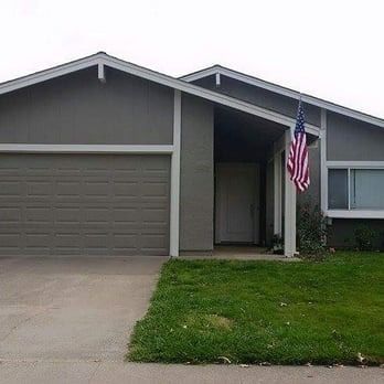 Single-story gray house with a garage, front lawn, and an American flag by the entryway
