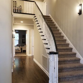 Hallway with a carpeted staircase, dark wood floors, and white walls leading to an upper landing