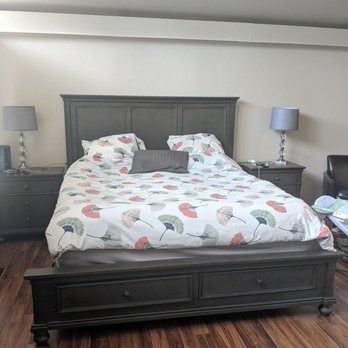 Dark wood bed with floral bedding between matching nightstands and lamps in a bedroom