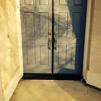 Closed gray double doors with gold handles at a sunlit building entrance