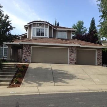 Two-story suburban house with a sloped driveway and three-car garage on a sunny day